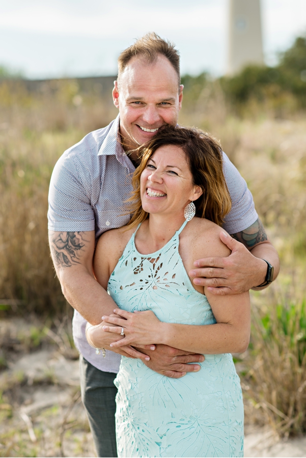 A man hugs his fiance on the beach.